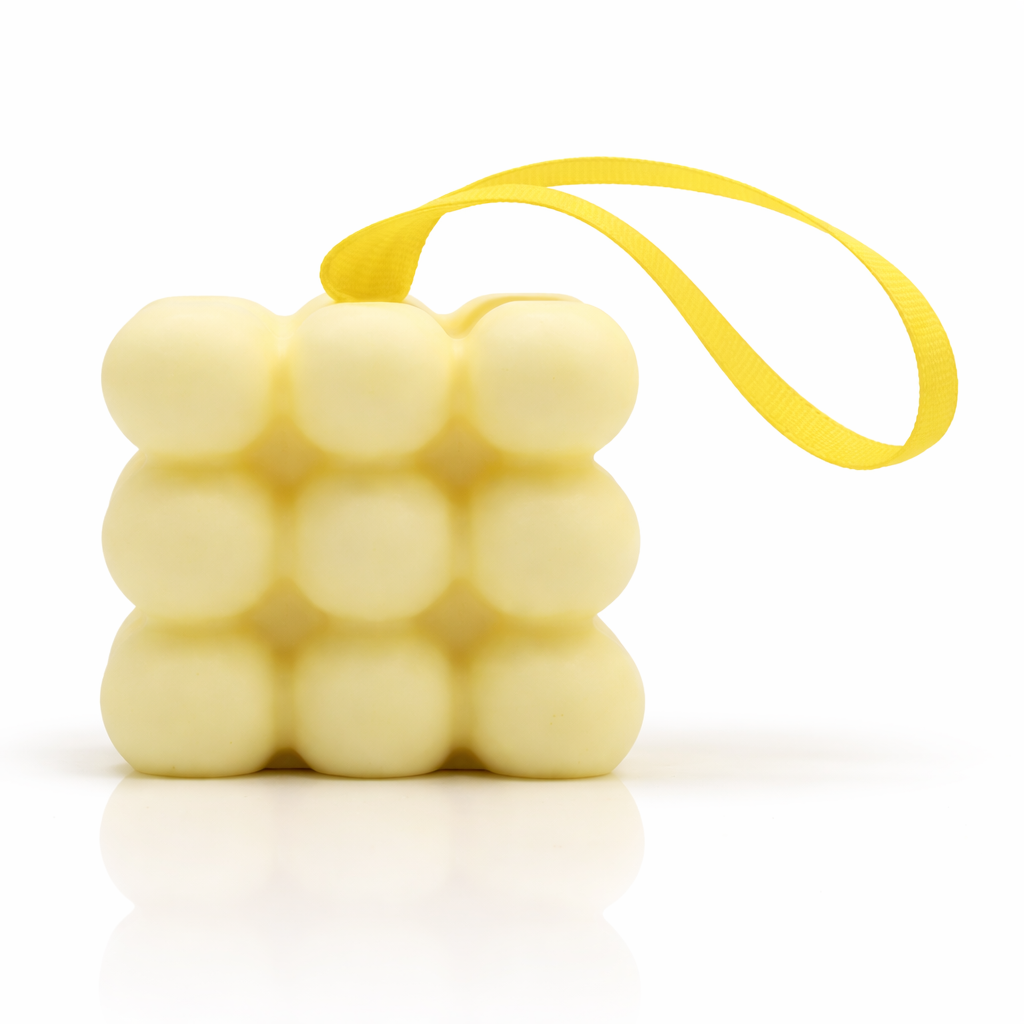 Yellow bubble massage soap with hanging ribbon, minimal clean white background with soft reflection, premium spa skincare product photography
