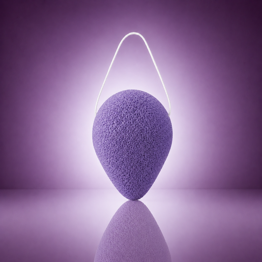 Lavender konjac facial sponge with a white hanging string on a soft purple background.