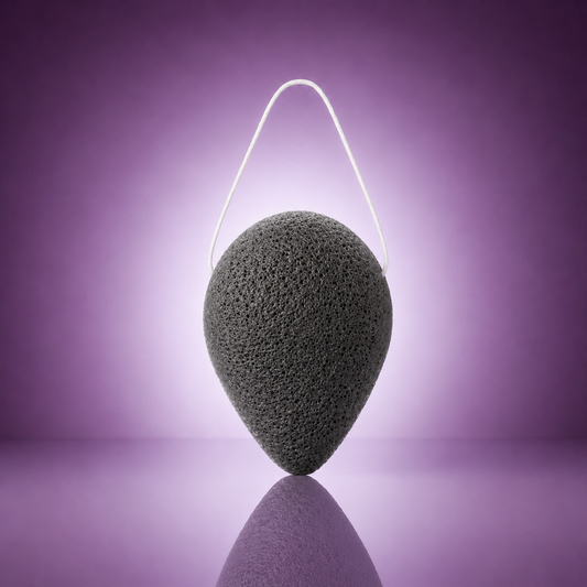 Purifying bamboo charcoal konjac sponge with a white hanging string on a soft purple background.