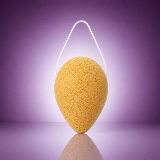 Turmeric konjac facial sponge with a white hanging string on a soft purple background.