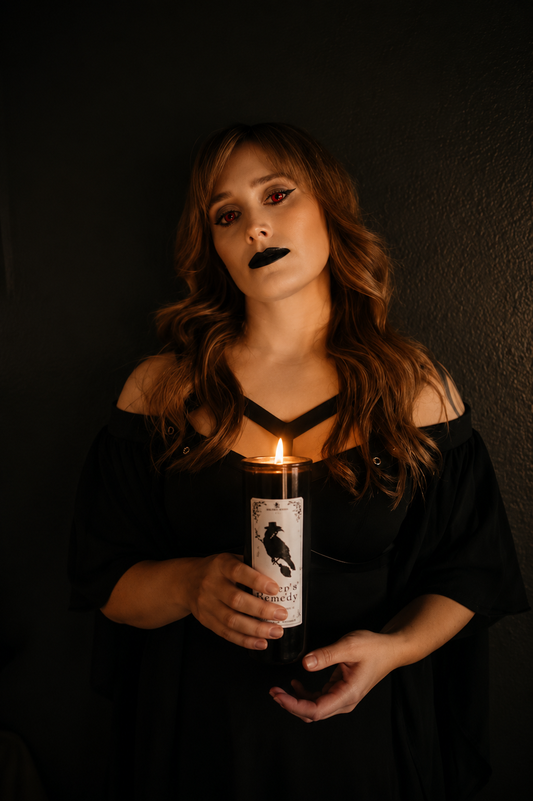 Woman holding a candle with a label featuring a raven against a dark background
