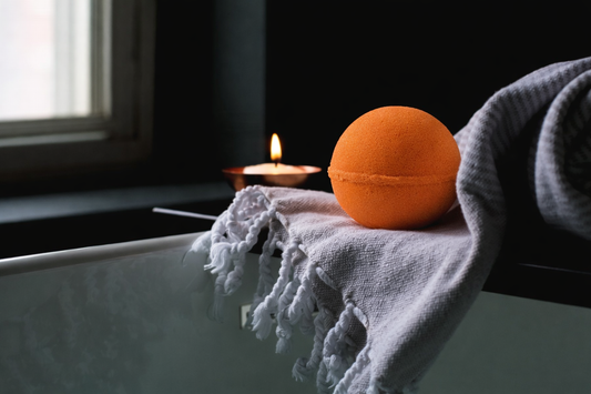 Vitamin C citrus bath bomb on bathtub with candle and towel – relaxing spa self-care scene