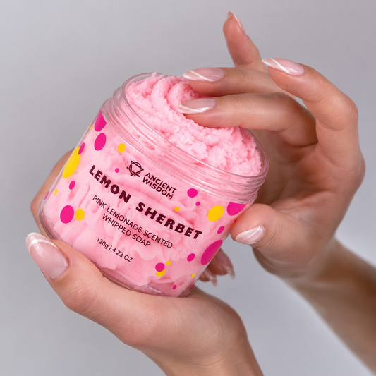 Hands holding an open jar of soft pink Lemon Sherbet and gently touching its creamy whipped-soap texture.