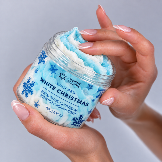 Woman holding an open jar of blue and white White Christmas Whipped Soap while gently touching its creamy texture.