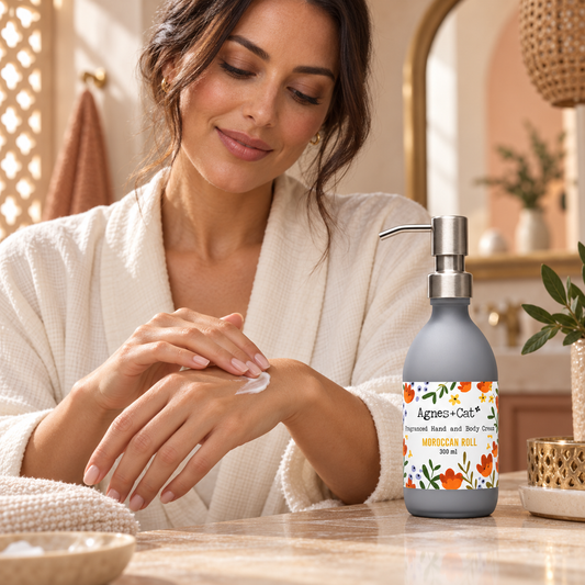 Woman applying Agnes + Cat Moroccan Roll Hand and Body Cream beside the 300ml pump bottle in a warm Moroccan-inspired bathroom