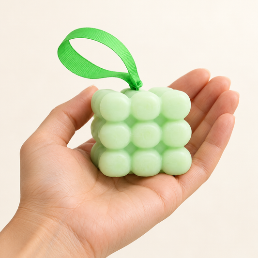 Spearmint and eucalyptus massage soap with a green hanging ribbon resting in an open hand to show its approximate size.