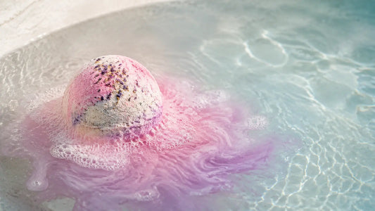 Pink and lavender bath bomb fizzing in clear water for a relaxing bath