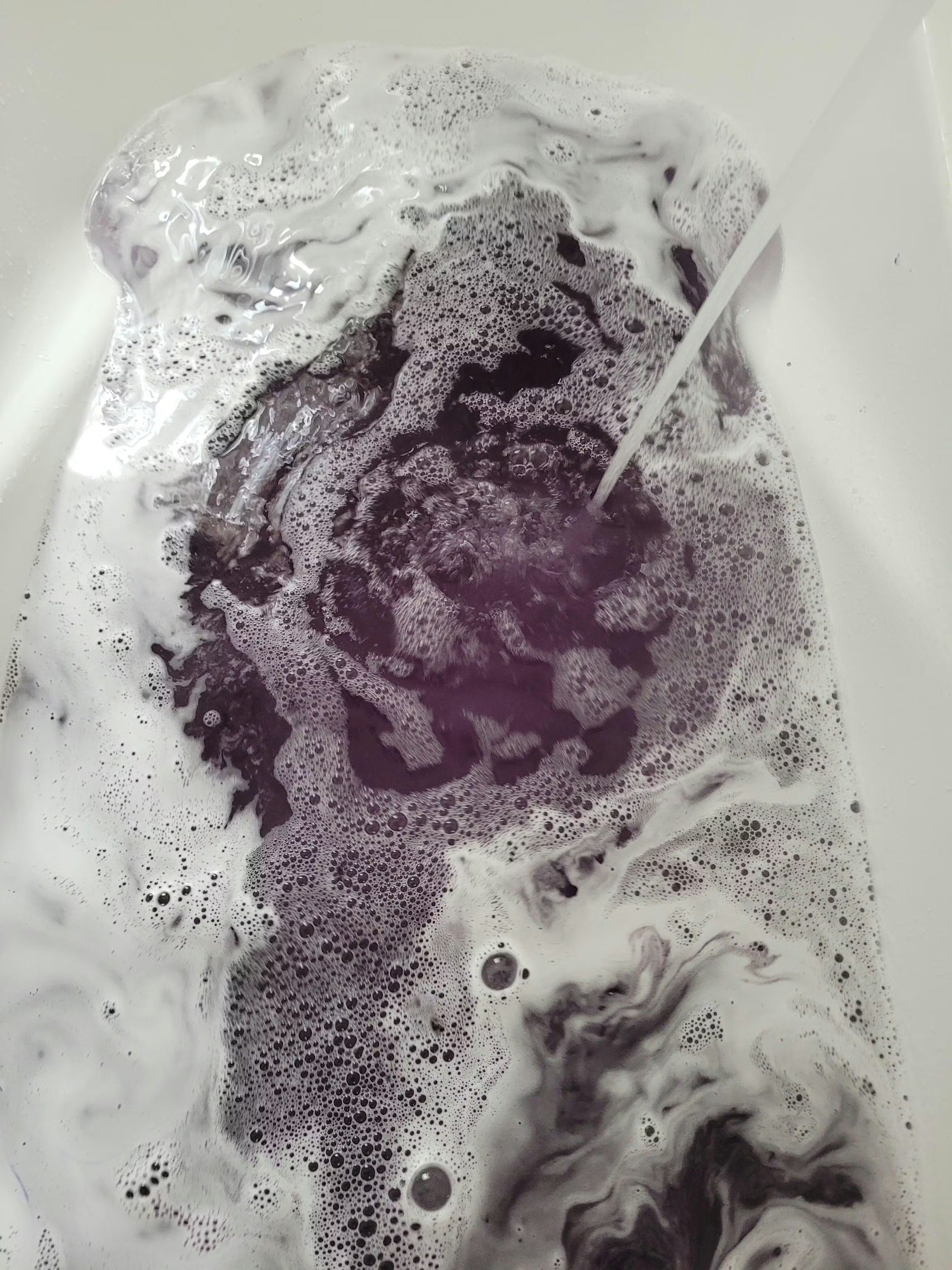 Skull bath bomb dissolving in water with dark and white foam – Lumaysa Halloween bath bomb