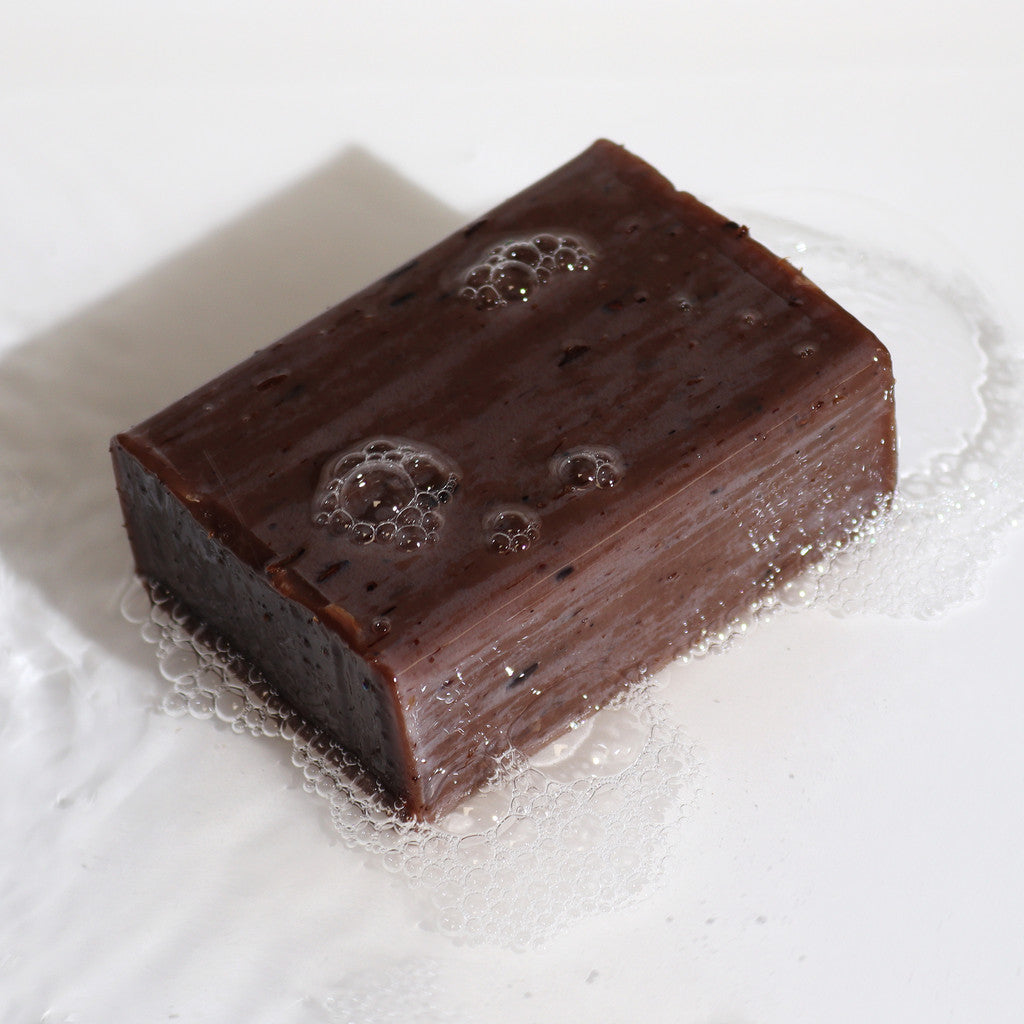 Natural Bar Soap – Lavender & Vanilla, dark brown bar with bubbles and light lather on a white surface.
