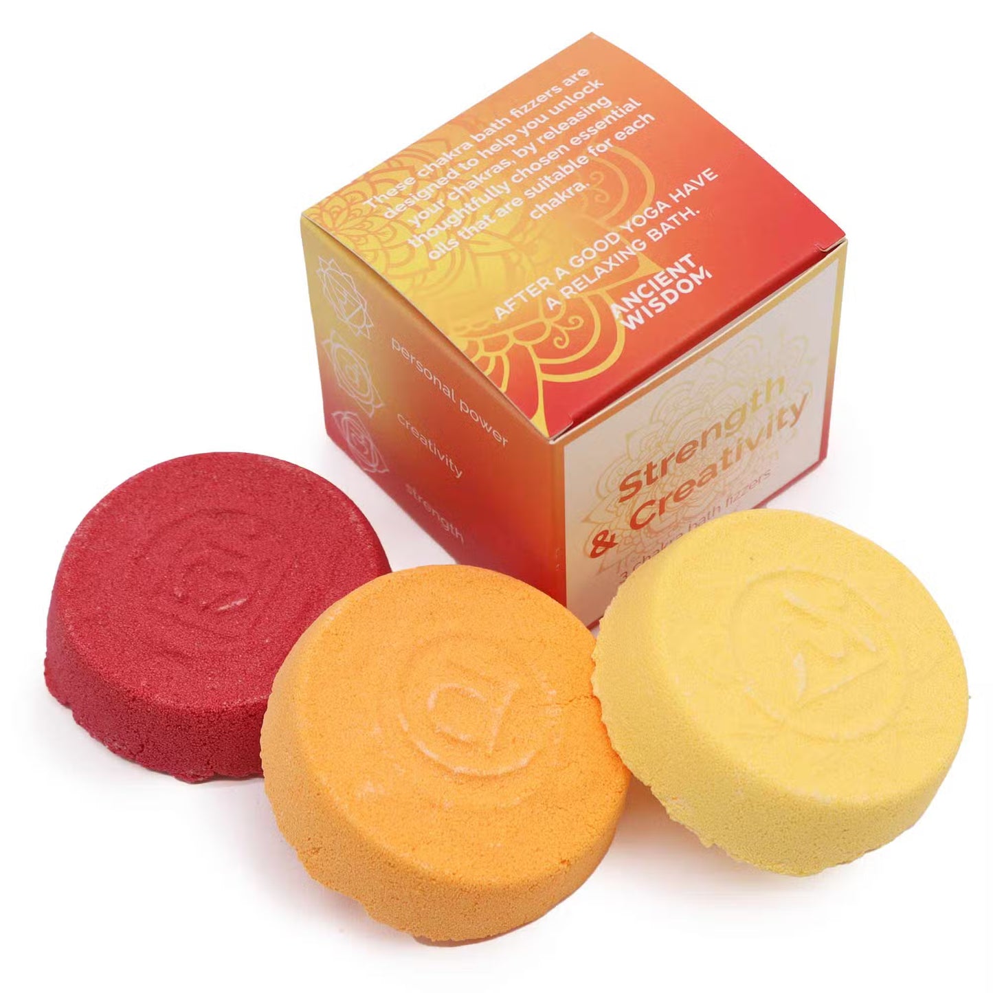 Three chakra bath fizzers in yellow, orange and red placed beside the Strength & Creativity gift box, showing a handcrafted wellness bath set for relaxation and gifting.