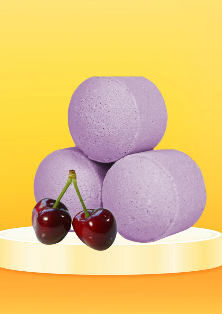 Black cherry bath bomb chill pills displayed on a yellow pedestal with fresh cherries, creating a vibrant premium spa aesthetic by Lumaysa.