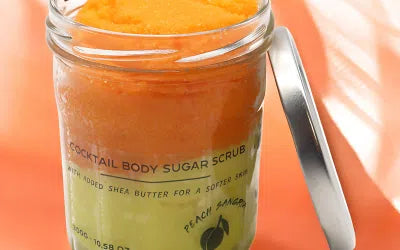 Lumaysa Sunset Glow Peach Sangria Sugar Body Scrub in a glass jar – layered orange and peach sugar scrub, photographed with an open lid on an orange background.