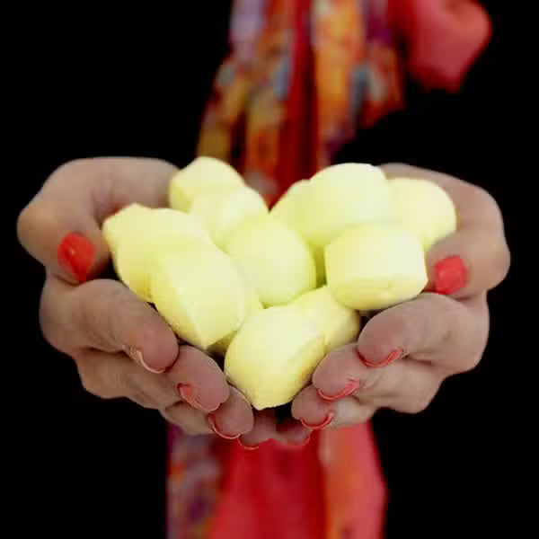Hands holding Lumaysa Pina Colada chill pills bath bombs, mini tropical bath fizzers with coconut and pineapple scent for relaxing bath rituals