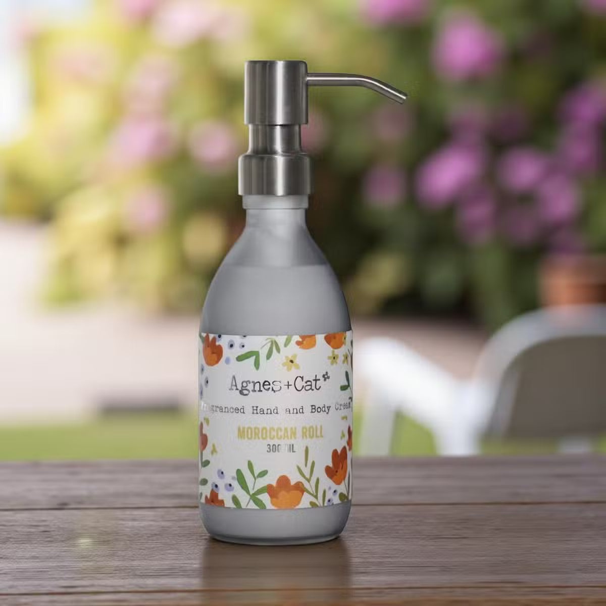 Lumaysa Moroccan Bliss Hand & Body Lotion 300ml in a matte grey pump bottle, styled on a rustic wooden surface with a soft, blurred outdoor background.