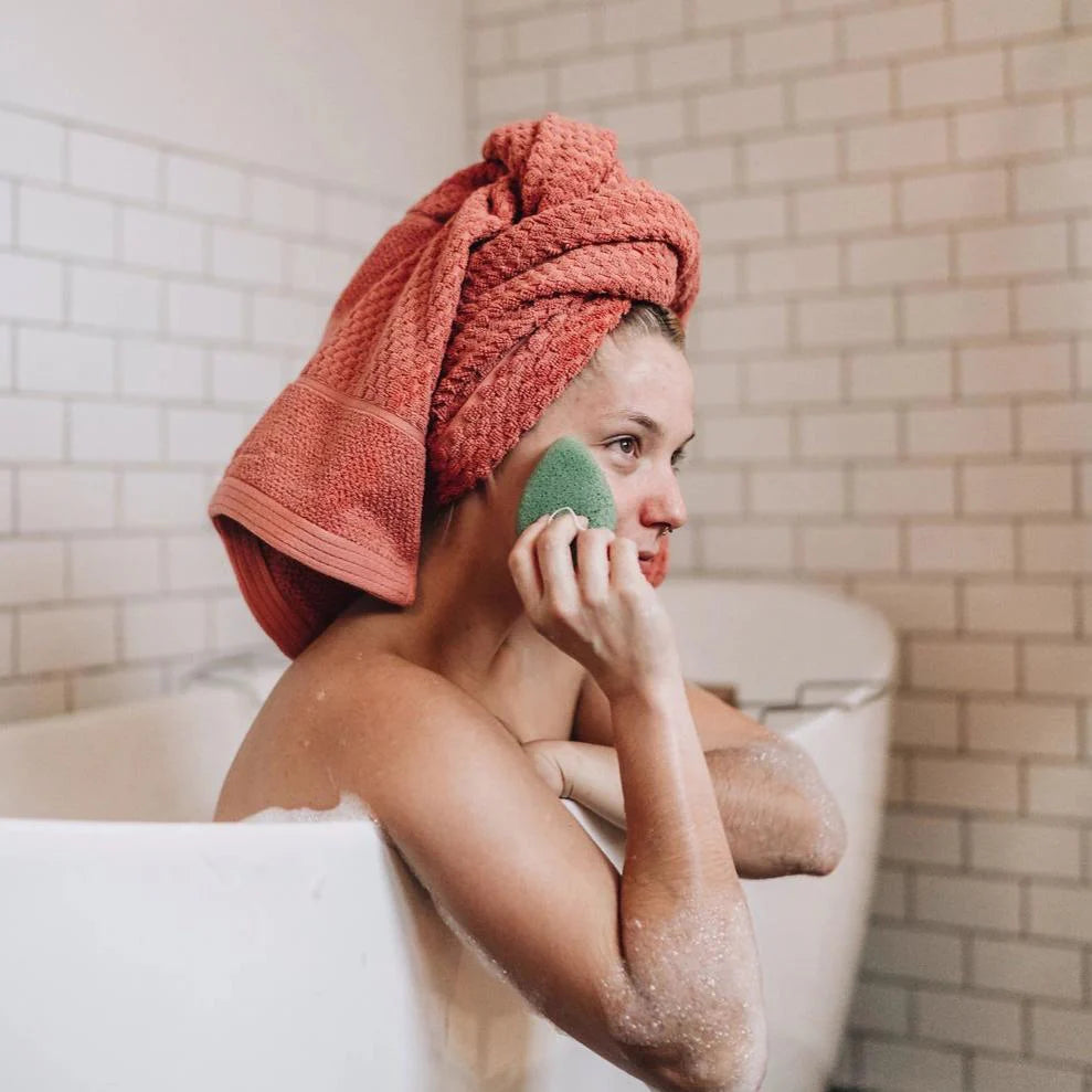 Woman using Lumaysa Green Tea Konjac facial sponge during a relaxing self-care and cleansing ritual