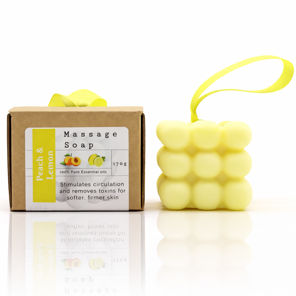 
Luxury massage soap set with peach and lemon packaging, featuring a yellow bubble-textured soap with ribbon, clean white background with reflection, premium European