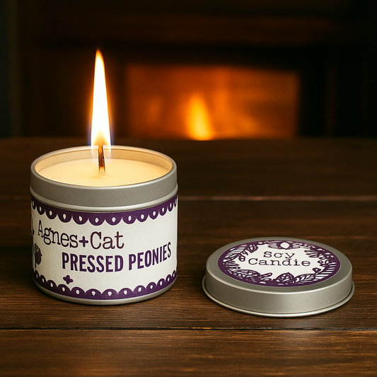 Pressed Peonies soy candle in tin by Lumaysa, lit candle on wooden surface with warm cozy background