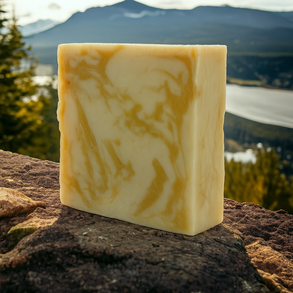 Lumaysa Silken Touch – Argan & Olive handmade soap bar standing on a rock with a scenic mountain and lake background.