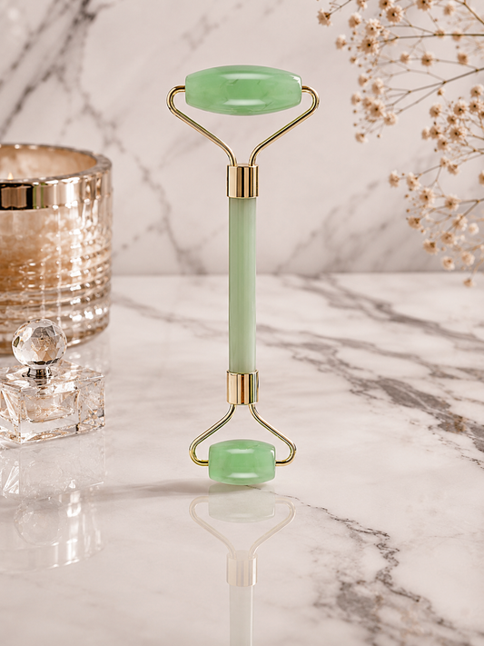 Green jade roller on a marble surface with decorative elements.