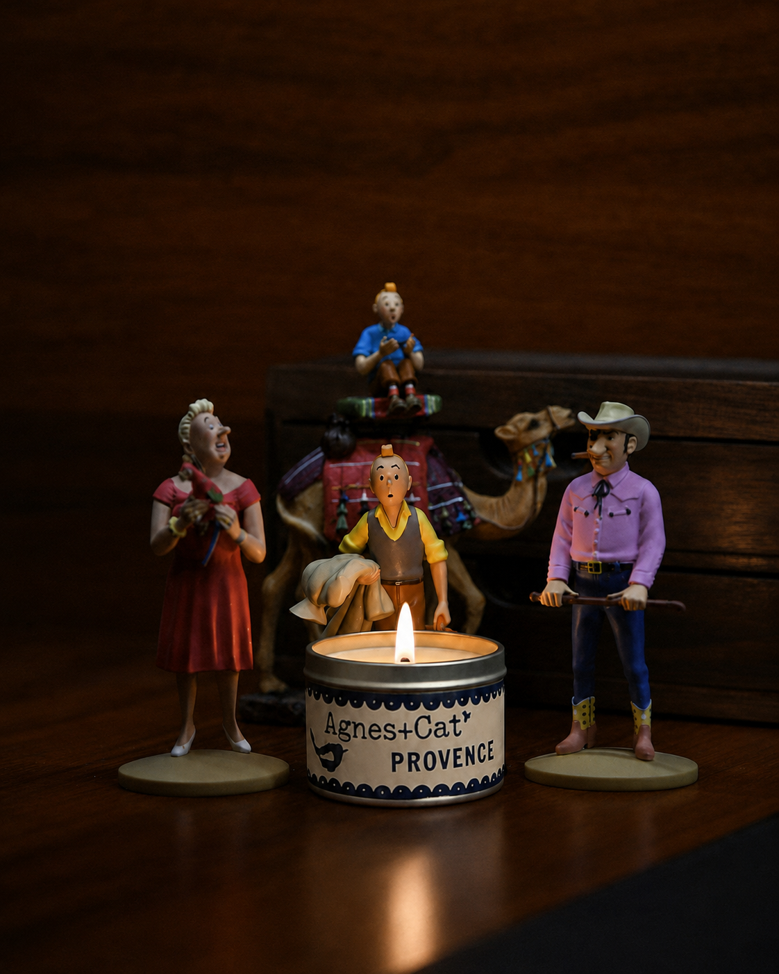 A glowing candle surrounded by vintage figurines on a wooden table in a warm, atmospheric setting