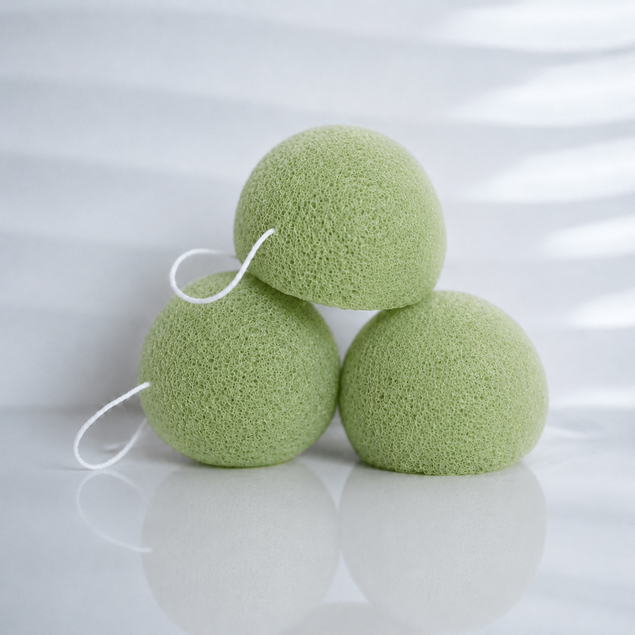 Three antioxidant green tea konjac sponges with white hanging strings on a clean white background.