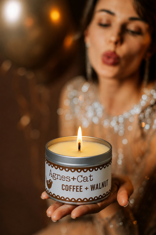 Woman holding a candle labeled 'Agnes + Cat Coffee + Walnut' with a blurred background
