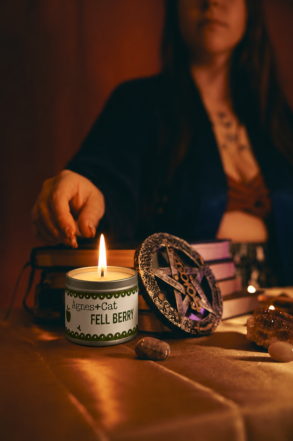 Person lighting a candle with a pentagram symbol on a table, surrounded by mystical items.