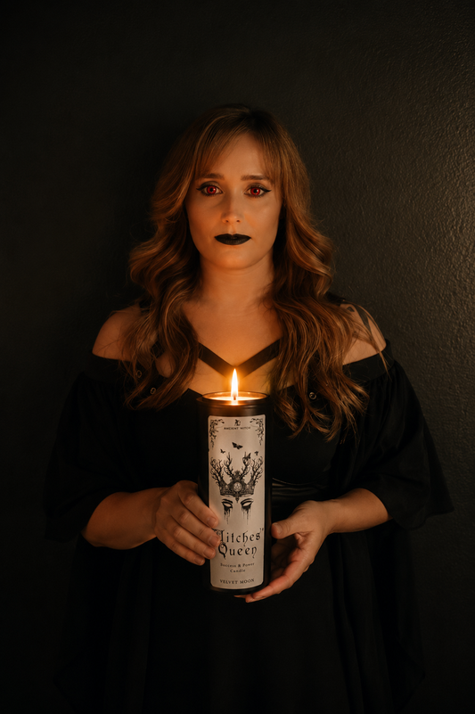 Woman holding a candle labeled 'Witch Queen' against a dark background