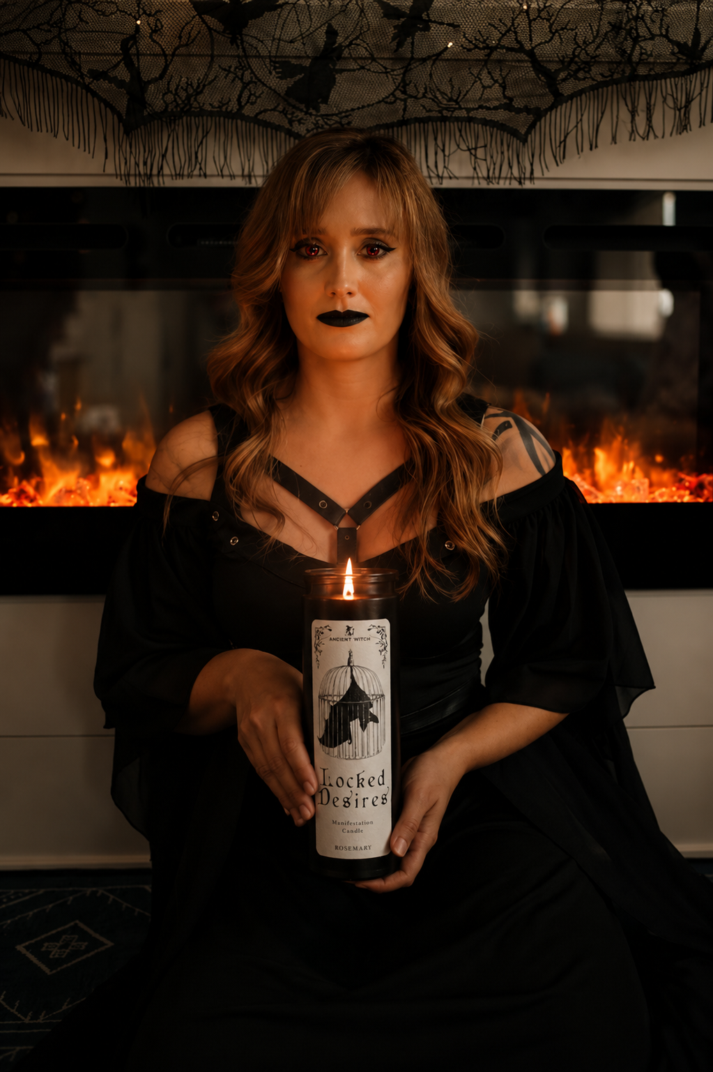 Woman holding a candle in front of a fireplace with decorative branches above.