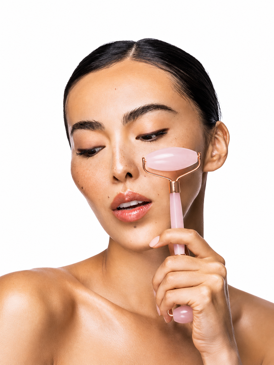 Woman using a pink skin roller on her face against a white background
