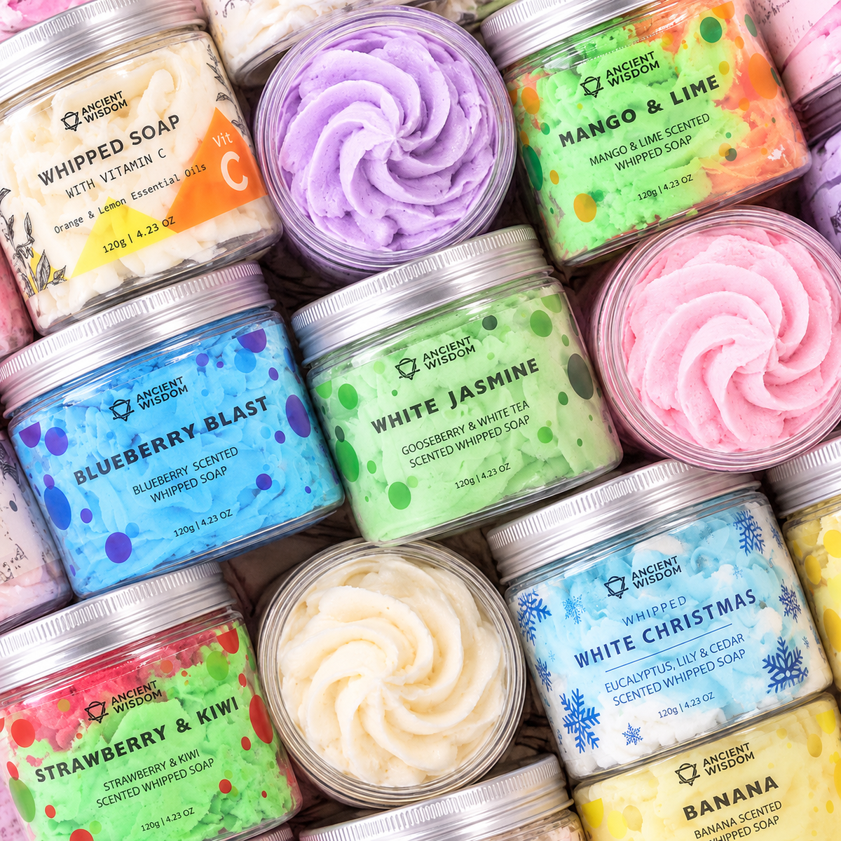 Overhead display of nine colourful Ancient Wisdom whipped soaps in open and closed jars, featuring fruity, floral and fresh scents.