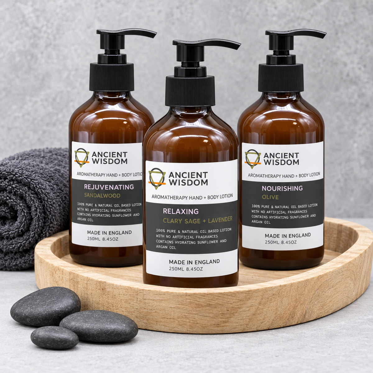 Ancient Wisdom Aromatherapy Hand and Body Lotions in Rejuvenating Sandalwood, Relaxing Clary Sage and Lavender, and Nourishing Olive scents displayed on a wooden spa tray.