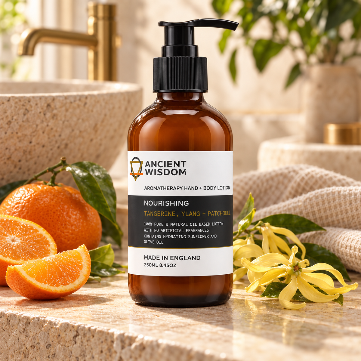 Ancient Wisdom Nourishing Hand & Body Lotion with Tangerine, Ylang and Patchouli, displayed with fresh tangerines and yellow flowers in a warm spa setting.