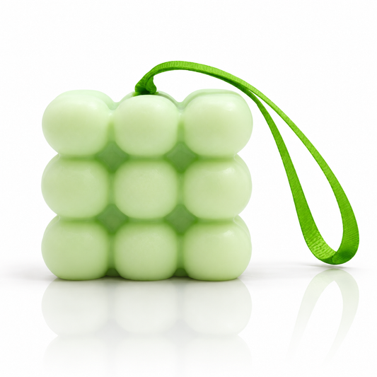 Pale green spearmint and eucalyptus massage soap with a green hanging ribbon on a white reflective surface.