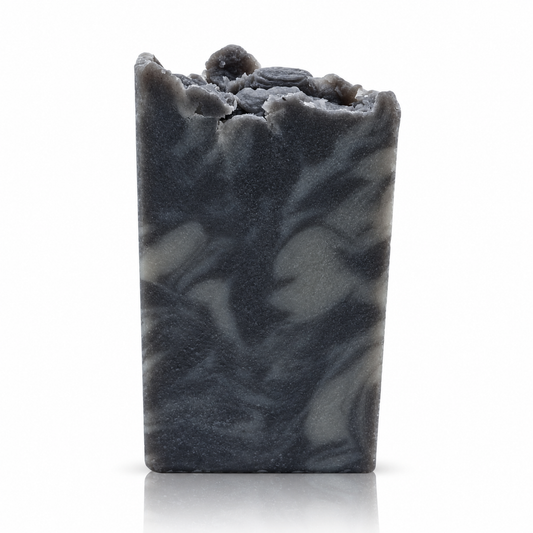 Dark grey handmade soap bar with lighter grey swirls and a sculpted top on a white background, with a soft reflection beneath.