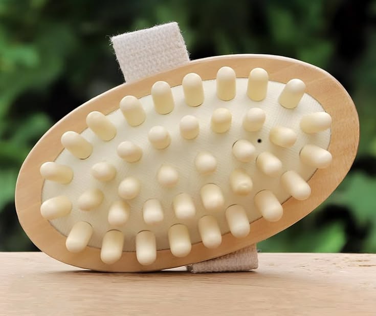 Wooden brush with white bristles on a wooden surface with a blurred green background