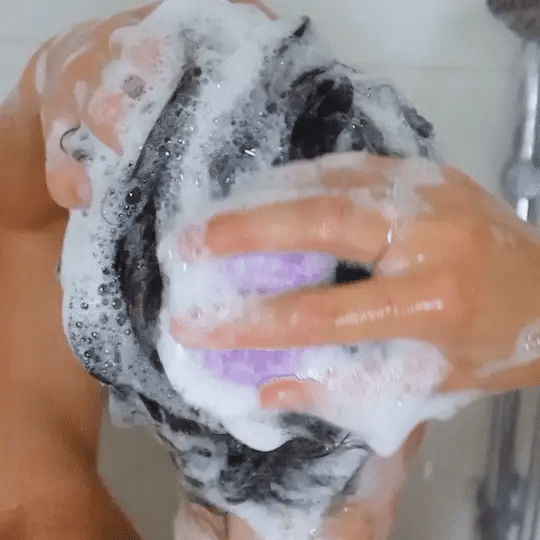 Woman lathering wet hair with a solid shampoo bar during washing