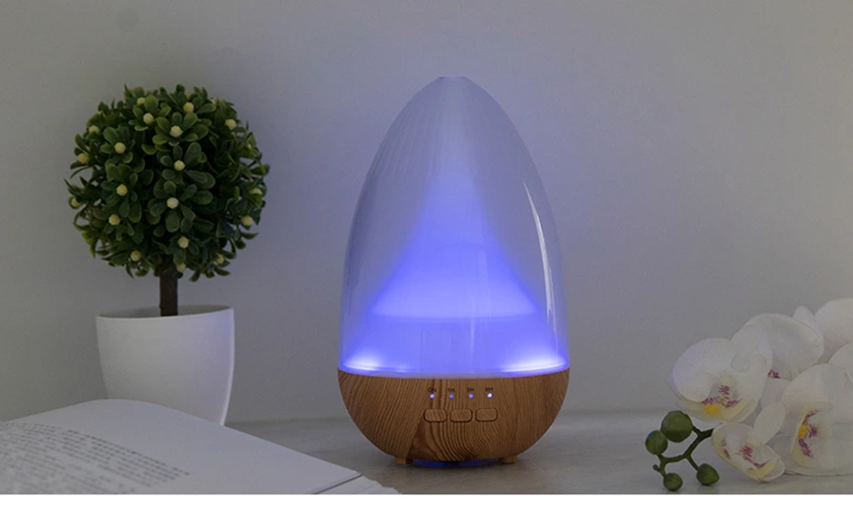 Lumaysa ultrasonic aroma diffuser with soft blue LED light and wood-effect base styled in a calm, minimal home setting