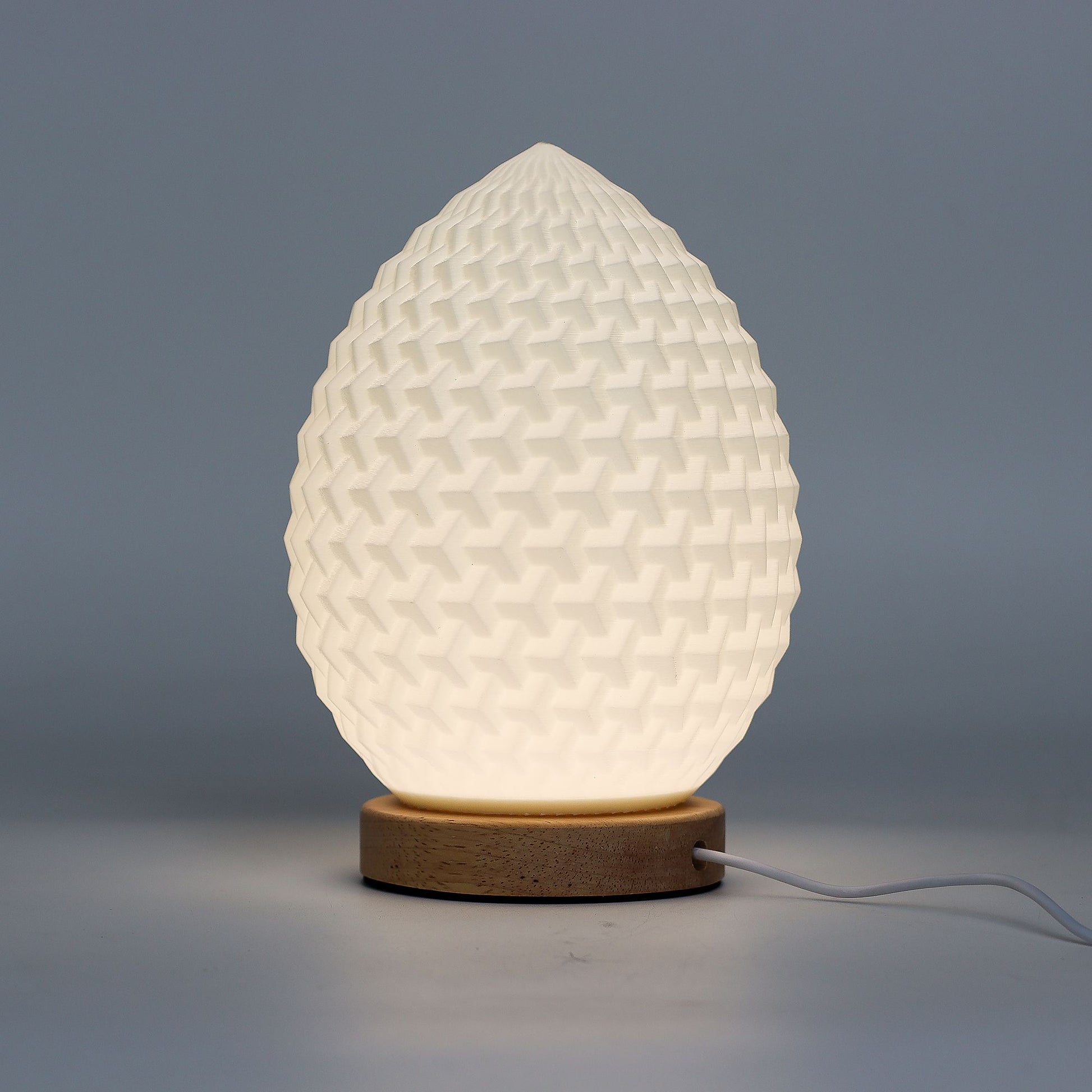 Lumaysa Aura Drop sculpted ambient table lamp with textured organic design and natural wooden base, emitting a soft warm glow