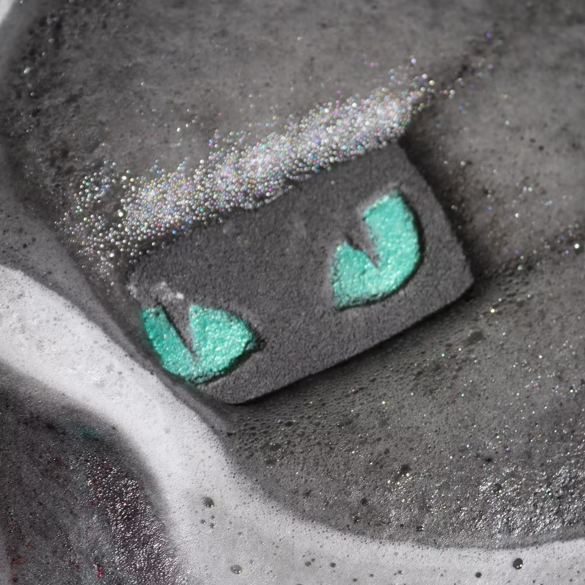 Cat eyes bath bomb dissolving in dark water with foam and shimmer, spooky Halloween bath experience with glowing effect