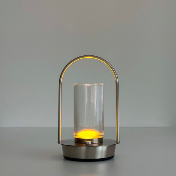 Lumaysa Crystal Lantern Touch Lamp with warm LED glow, featuring a transparent glass cylinder and brushed metal base, USB-C rechargeable ambient table lamp on a minimalist grey background.