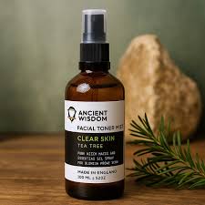 Lumaysa Tea Tree Clear Purifying Toner Mist in an amber glass bottle on a wooden surface with rosemary and a natural green background, made with witch hazel and tea tree essential oil for blemish-prone skin.