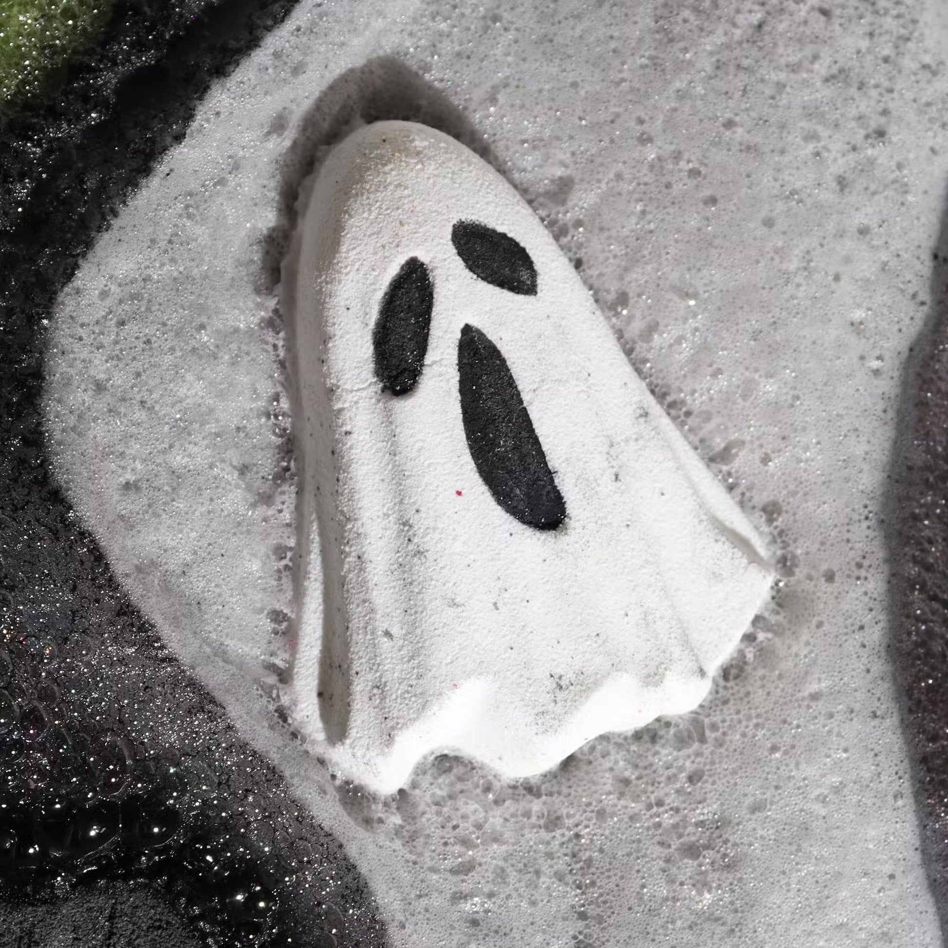 Ghost-shaped bath bomb dissolving in foamy water with dark contrast, relaxing Halloween bath ritual and spooky self-care experience
