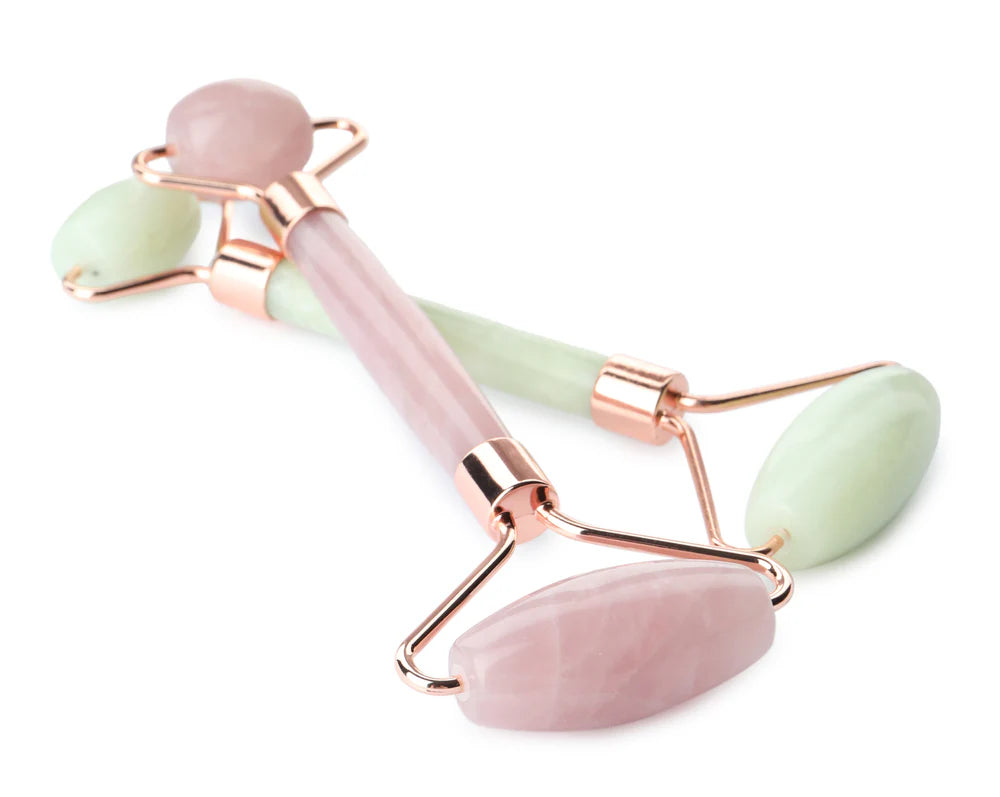 Pink and green facial roller with rose gold accents on a white background