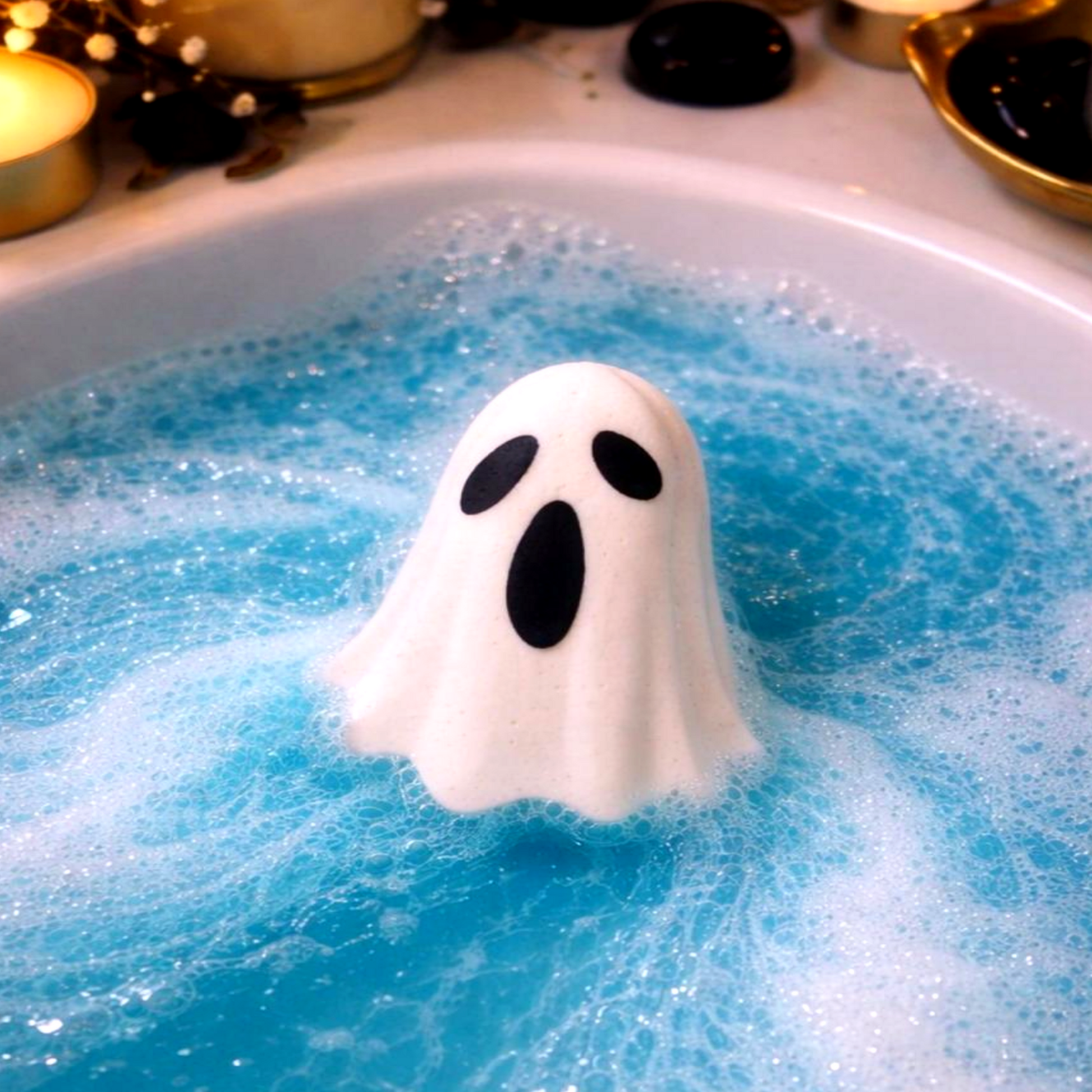 Ghost bath bomb dissolving in blue water with foam and candles, relaxing Halloween self-care bath experience