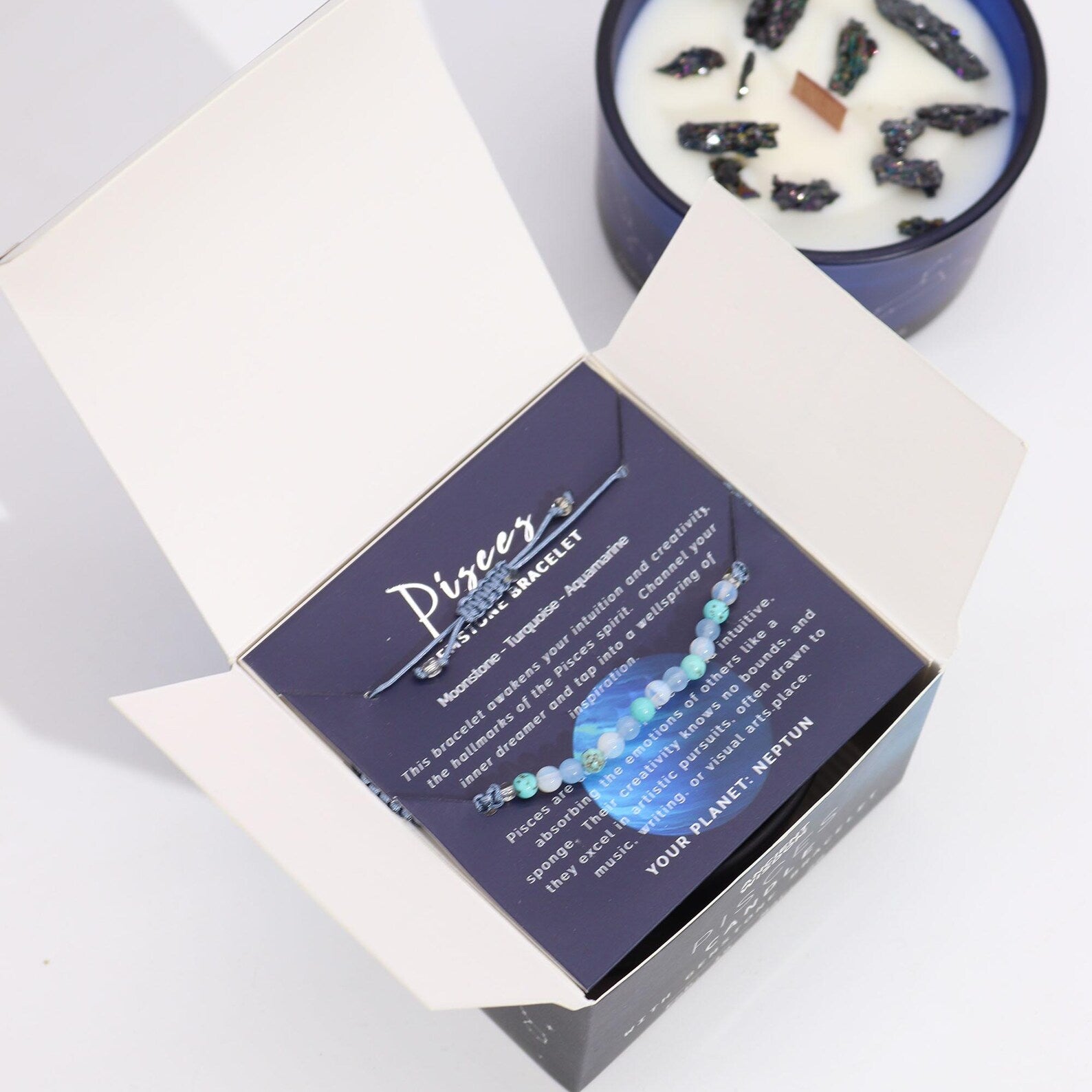 Pisces zodiac bracelet displayed inside an open gift box with a blue candle in the background.