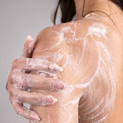 Woman gently massaging whipped soap onto her shoulder, creating a rich, creamy lather.