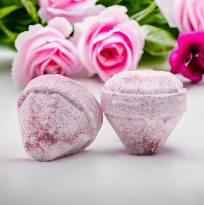Two Lumaysa Gemstone Bath Bombs in Very Berry fragrance, handcrafted crystal bath bombs displayed with pink roses, luxury self-care bath product